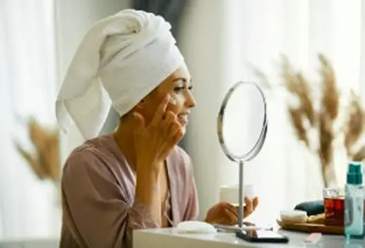 beautiful lady looking in mirror applying natural face cream