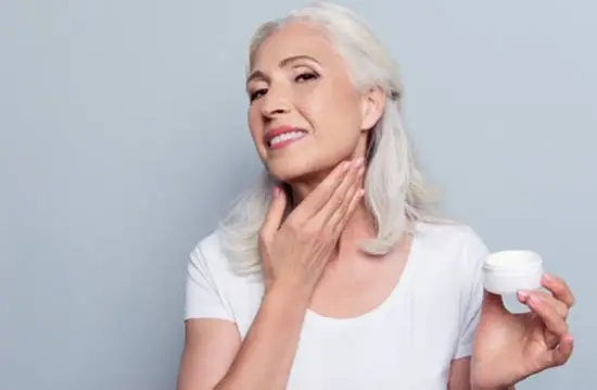 A mature lady applying natural face cream around her lower face and neck area